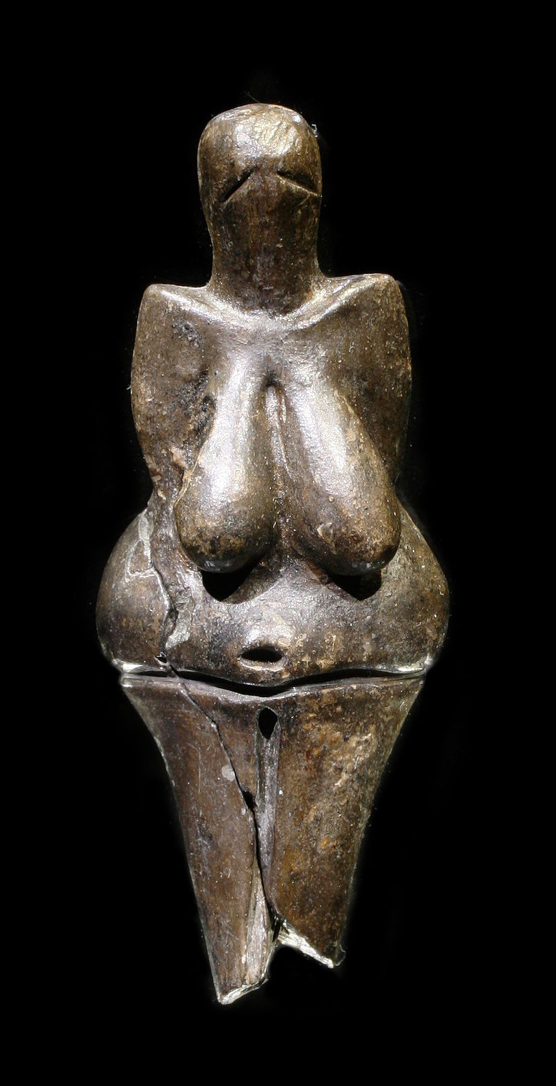 Abartılmış göğüsleri ve kalçasıyla kadın vücudunu temsil eden, parlak koyu renk taştan yapılmış bir heykel. Heykelin yüz hatları yoktur ve iki kolu da görünmemektedir.